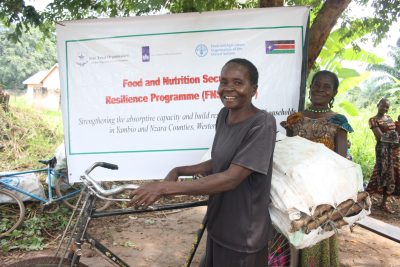 A female benficiary posing with TME-14 on her bicycle in Nzara